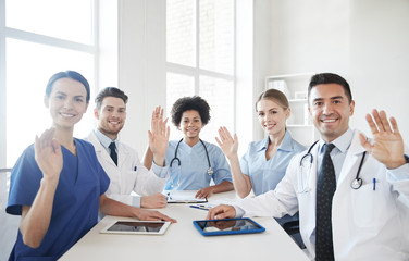 happy doctors meeting and waving hands at hospital
