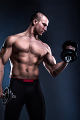 Fototapeta na wymiar bodybuilder lifting dumbbells on blue background