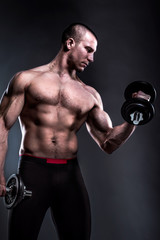 Fototapeta na wymiar bodybuilder lifting dumbbells on dark background