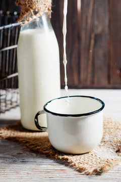 
milk in the bottle , jug and cup on the wooden background