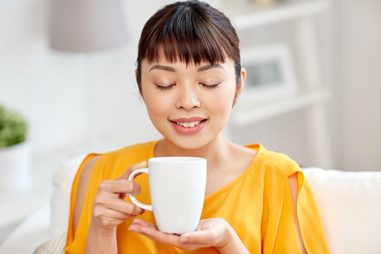 happy asian woman drinking from tea cup