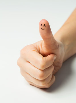 close up of hand showing thumb with smiley face