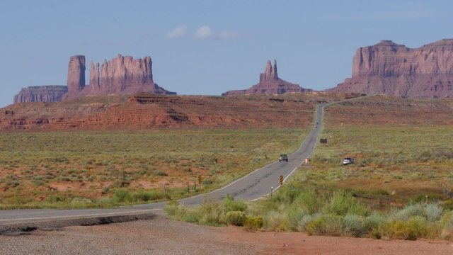 A truck passes through scenic Monument Valley