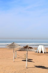 Sonnenschirme werfen kreisrunde Schatten auf Strand, Surfbretter sind im Kreis aufgebaut