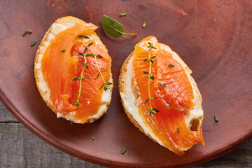 delicious sandwich with smoked salmon, cream cheese and thyme on rustic ceramic dish
