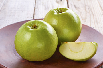 Two green apples on rustic ceramic plate