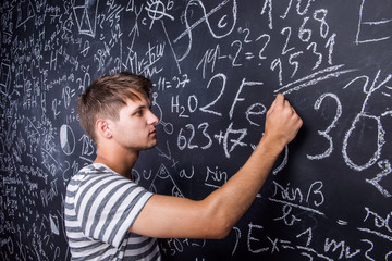 Student writing on big blackboard with mathematical symbols