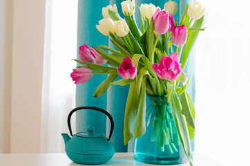 Bouquet of beautiful pink and yellow tulips in tiffany vase, cup, saucer and teapot. Free space for...