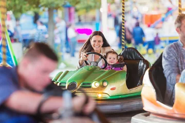 Tuinposter Amusementspark Moeder en dochter in botsauto op kermis