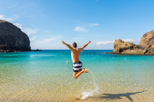 Happy man jumping over the tropical beach