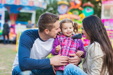 Father, mother and daughter having fun in amusement park