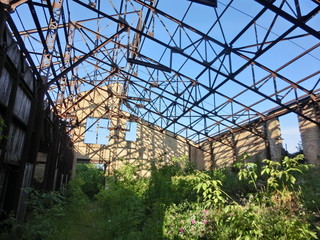 Abandoned industrial warehouse with missing roof, rusty beams - landscape color photo