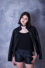 teen girl posing in a studio on a dark background in leather jac