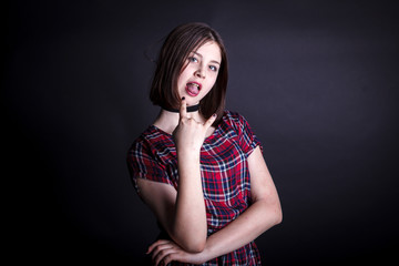 teen girl in a checkered dress posing on a dark background