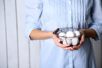 Obraz na płótnie Canvas Eggs in basket in women hands on wooden background