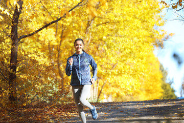Fototapeta premium Young beautiful woman jogging in autumn park