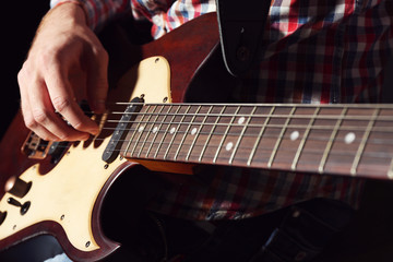 Fototapeta premium Young man playing on electric guitar close up