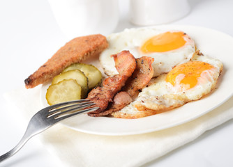 fried eggs with bacon and toasts on white background
