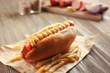 Hot dog with fried potatoes on craft paper