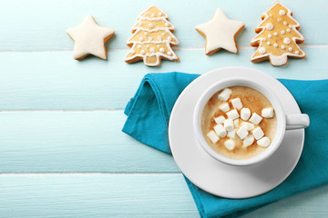 Cup of hot cacao with marshmallow, cookies and napkin on blue table