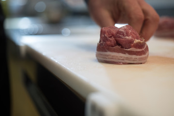 chef prepares a portion of tenderloin with bacon