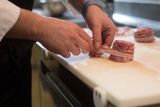 chef prepares a portion of tenderloin with bacon