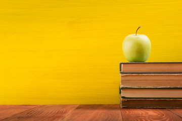 Stack of hardback books, diary on wooden deck table and yellow background. Back to school. Copy Space. Education background
