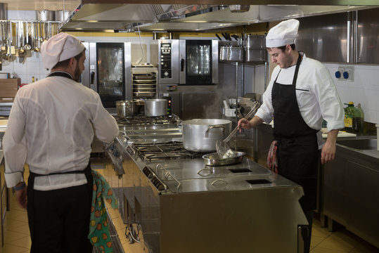 chefs cook and move around in the restaurant kitchen