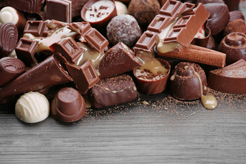Assortment of tasty chocolate candies and cinnamon on wooden table background