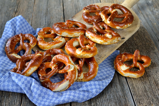 Ofenfrische handgemachte bayerische Brezen auf einem alten Backbrett - Oven fresh handmade Bavarian pretzels on a vintage baking board