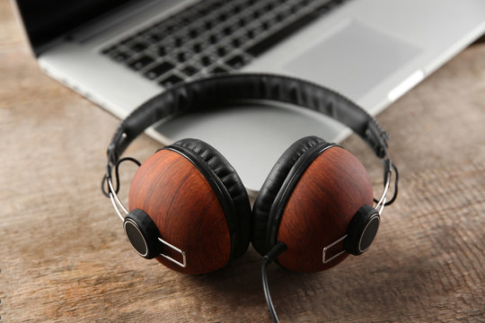 Laptop and earphones on wooden background