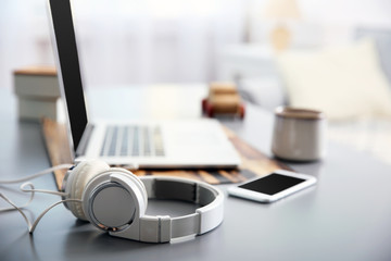 Obraz premium Headphones, phone and laptop on white table against defocused background