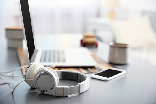 Headphones, phone and laptop on white table against defocused background