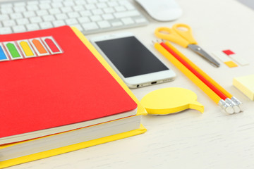 Workplace with mobile phone, keyboard and stationery on light table