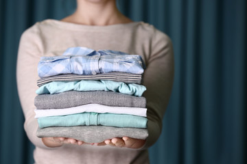 Woman holding washed and dried clothes on curtain background