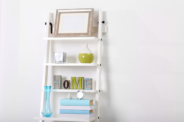 White bookcase with books and accessories in the room