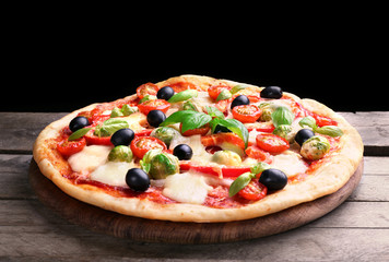 Delicious pizza with cheese and vegetables on black background