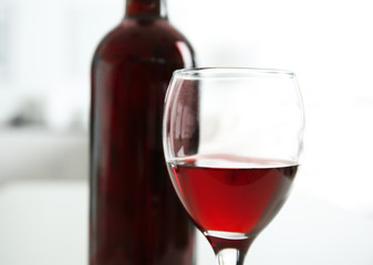 Glass of red wine with bottle on blurred interior background