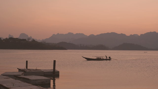 The boat floats on the lake at sunset