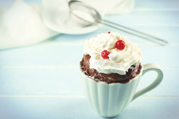 Mug cake with cream and cranberry on blue wooden background