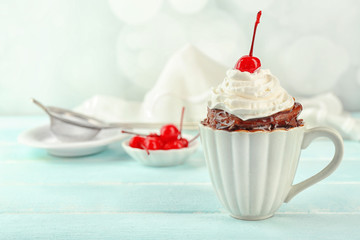 Chocolate mug cake with cream and cherry on a table
