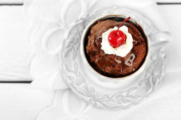 Chocolate mug cake with cream and cherry on a white napkin