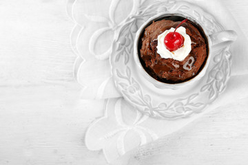 Chocolate mug cake with cream and cherry on a white napkin