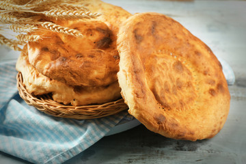 Flat bread and wheat ears on napkin on wooden background
