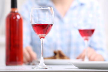 Dinner with glasses of wine at table on light blurred background