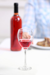Dinner with glass of wine at table on light blurred background