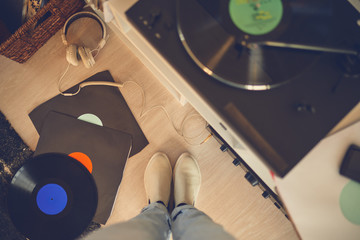 Bird eye view of female legs among vinyl records and gramophone