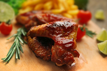 Grilled chicken wings with French fries and garden-stuff on cutting board