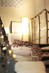 Resting-place with electric garland, bedspread, pillow and lamps on modern stairs