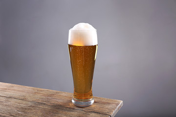 Glass of light beer on grey background